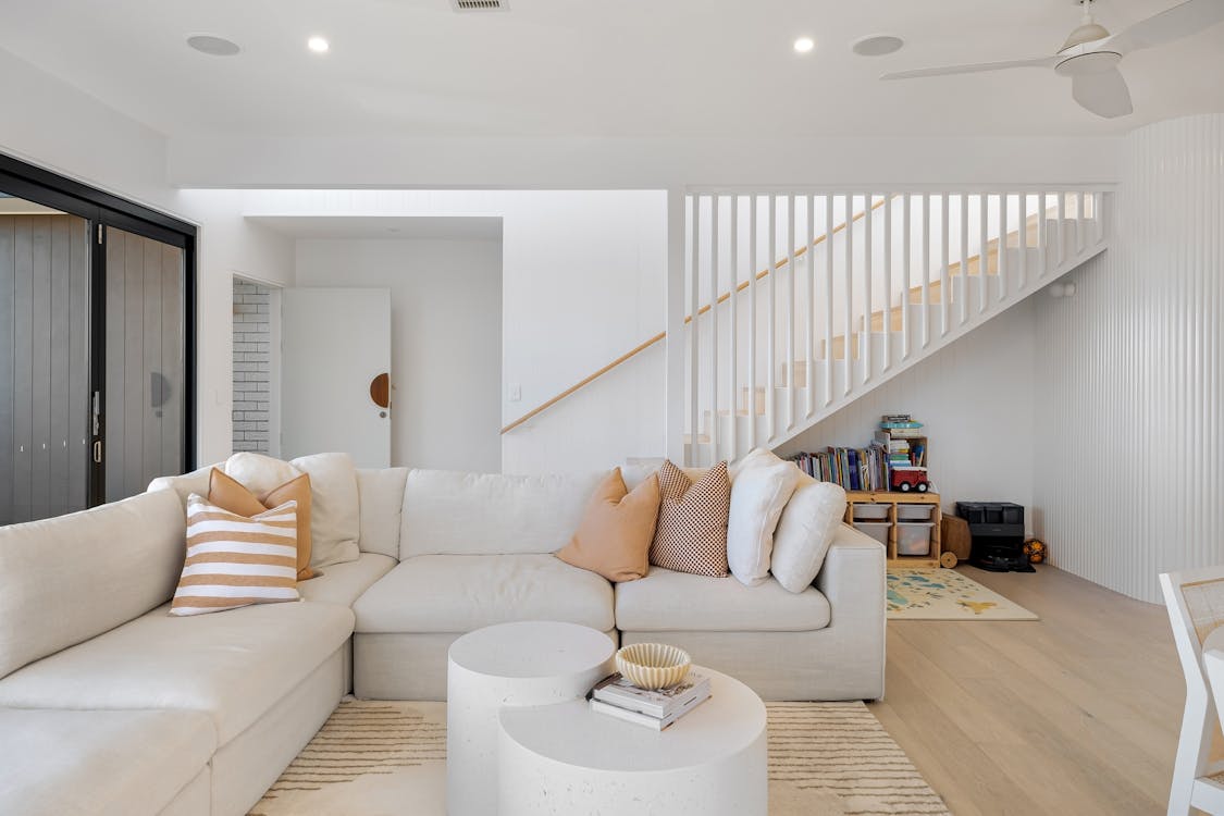 Crisp White Modular Sofa Anchored by Textured Ribbed Wall and Elegant Spindle Staircase