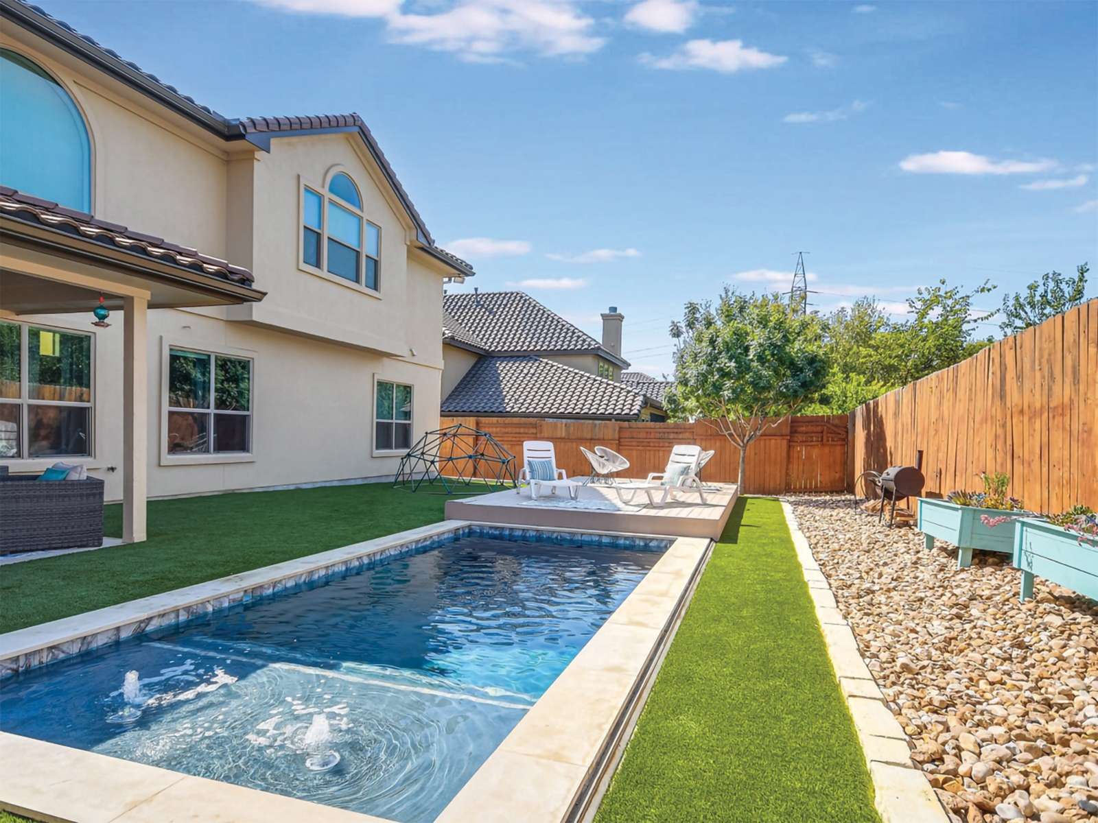 Elegant Pool Surroundings Featuring Synthetic Grass and Decorative Rocks